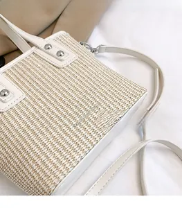 Detail of off-white woven texture handbag with silver studs and a thin shoulder strap