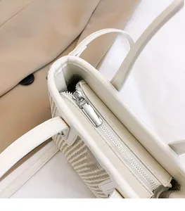 Close-up of the smooth silver metal zipper and woven texture on a beige handbag