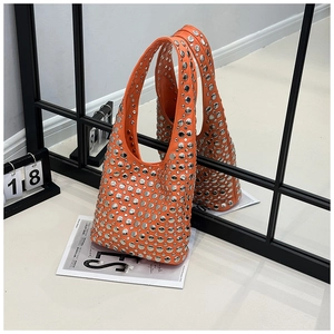 Close-up detail of silver metal studs on an orange half-moon studded shoulder bag