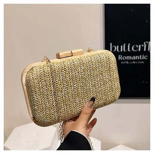 Detail of straw woven handbag with wooden frame and sleek gold metal chain strap
