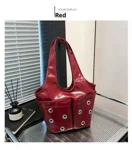 Detail of red patent leather shoulder bag featuring dual front pockets and silver eyelets