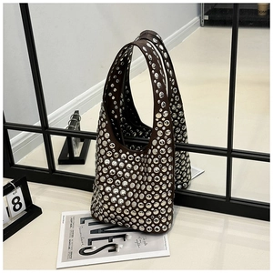 Close-up of dark brown leather underarm bag with dense silver metal rivet detailing