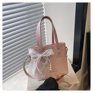 Detail of pink straw bag with white lace bow, pearl charms and fashion text print