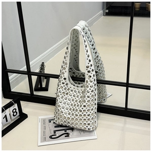 Close-up of white leather hobo bag featuring dense silver studs and mirror reflection