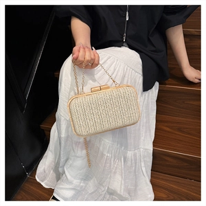 Detail of straw woven clutch with solid wood frame and gold metal chain strap