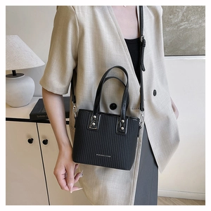 Detail of black striped tote bag worn crossbody showing fashion and bags text and silver studs