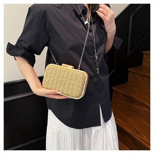 Detail of hand-woven straw clutch bag with minimalist wooden clasp and gold metal frame