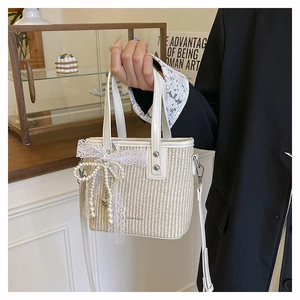 Detailed shot of white straw bucket bag with pearl tassels and lace bow decoration