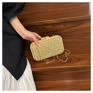 Detail of straw woven handbag with V-shaped texture, wooden lock, and gold chain strap