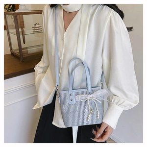 Detail of light blue woven handbag with lace bow and pearl heart pendant charm