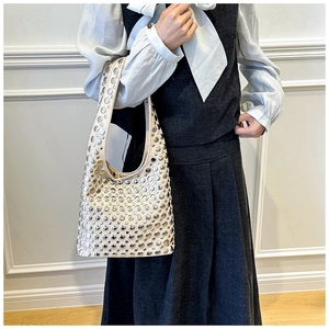 Detail of cream underarm bag featuring silver rivets and elegant leather texture