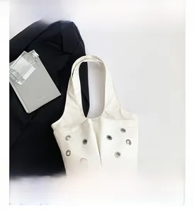 Detail of white PU leather tote bag with silver eyelets and minimalist shoulder strap design