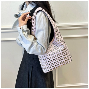 Side view of pink shoulder bag with silver rivet details worn by a model