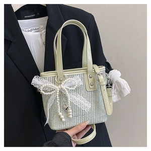 Detail of light green woven mini handbag with pearl lace bow and heart metal pendant