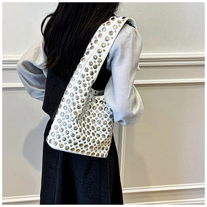 Detail of white leather shoulder bag featuring dense silver stud rivets and a wide strap