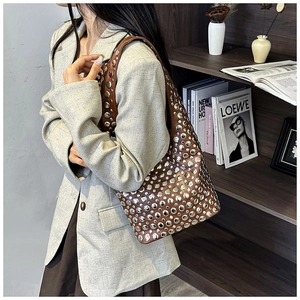 Close-up of brown leather hobo bag featuring silver metal studs in a stylish setting