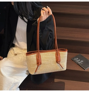 Detail of hand-woven straw tote bag with brown leather accents and knotted rope strap