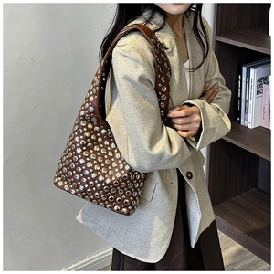 Close-up of brown punk-style leather bag with decorative silver metal studs
