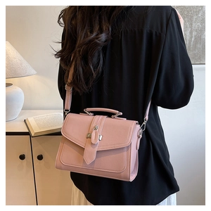 Pink lychee grain leather handbag with adjustable strap shown in a cozy interior setting