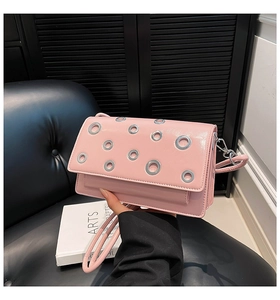 Close-up of pink rectangular shoulder bag featuring metallic silver grommet decorations