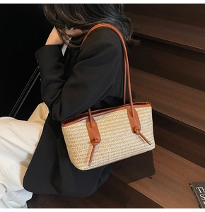 Detail of minimalist straw woven tote bag with brown leather knotted shoulder strap