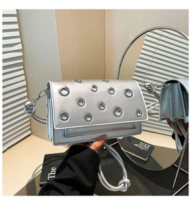 Detail of silver metallic purse featuring circular eyelets and elegant chain strap
