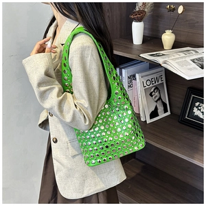 Detail of neon green underarm bag with silver studs worn by model in a chic setting