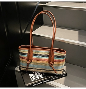 Close-up of a colorful striped woven tote bag with brown faux leather shoulder straps