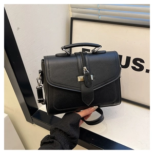 Detail view of black lychee grain texture with metal buckle on leather shoulder bag
