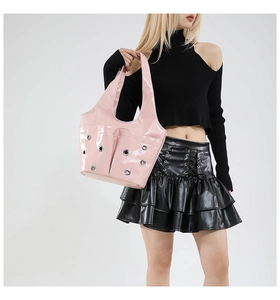 Detail of pink patent leather handbag with silver metal eyelets and double front pockets