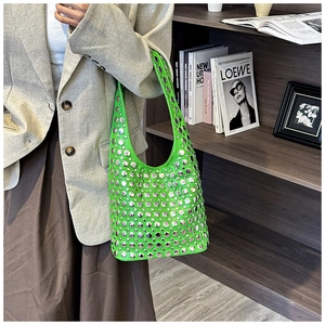 Detail of bright green studded hobo bag showing silver rivet texture and moon shape
