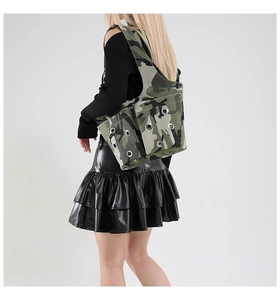Detail of camouflage shoulder bag featuring silver metal eyelets and rugged canvas texture