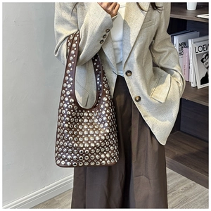 Detailed close-up of dark brown leather hobo bag featuring silver studded punk hardware