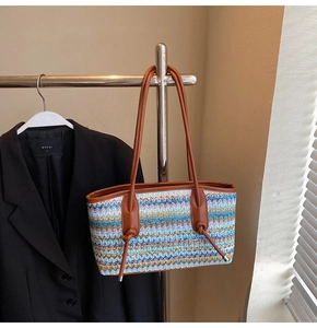 Detail of colorful woven tote bag with wave patterns and brown leather shoulder straps
