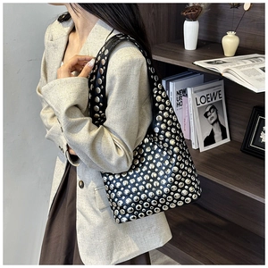Close-up detail of silver studs on black leather shoulder bag with stylish urban texture