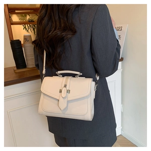 Detail of cream white leather shoulder bag showing the pebble texture and metal buckle