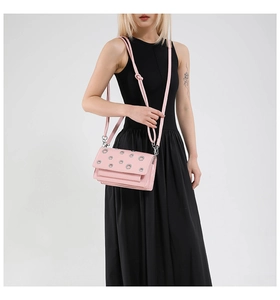Pink rectangular crossbody bag with silver eyelet studs and knotted strap on model
