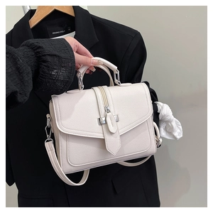 Close-up of beige lychee pattern handbag with silver hardware held by a model