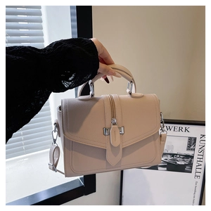 Detail of cream lychee texture leather handbag featuring metallic hardware and elegant handle