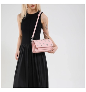 Detail view of pink crossbody bag featuring decorative metal eyelets and a sleek strap