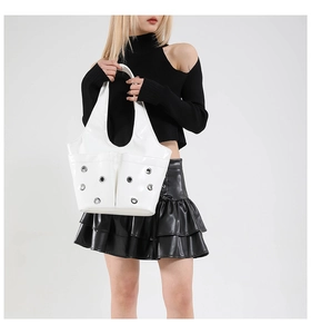 Detail of white glossy underarm bag featuring two front pockets and silver metal eyelets
