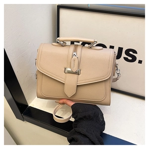 Detail of lychee textured beige crossbody bag showing silver buckle and leather strap
