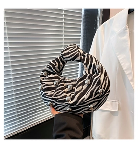 Detail of zebra pattern handbag with silver rivets and unique knotted handle design