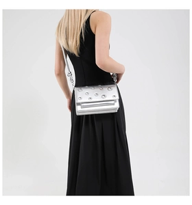 Detail of silver metallic crossbody bag with eyelet decor and knotted strap on model