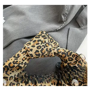 Detail of leopard print fabric handbag with knotted handle and silver metal rivets