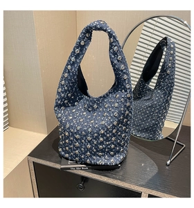 Detailed close-up of a blue denim hobo bag with silver studs and sparkling sequins