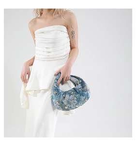 Close-up of floral tote bag with silver studs carried by a model in a white dress