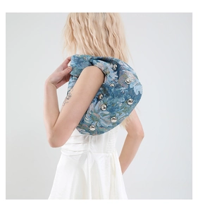 Detail of blue jacquard underarm bag with silver rivets and unique knotted shoulder strap
