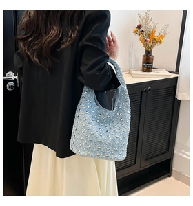 Close-up of light blue denim hobo bag featuring silver rivets and rhinestone embellishments