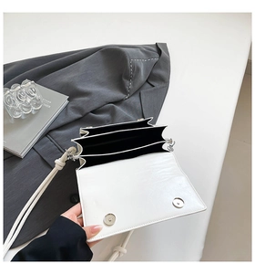 Detail of the white crossbody bag showing triple gusset compartments and magnetic snaps